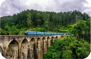 Blue train crossing the historic Nine Arches Bridge surrounded by lush greenery in Sri Lanka